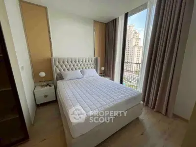 Luxurious bedroom with elegant decor and stunning city view from large windows.