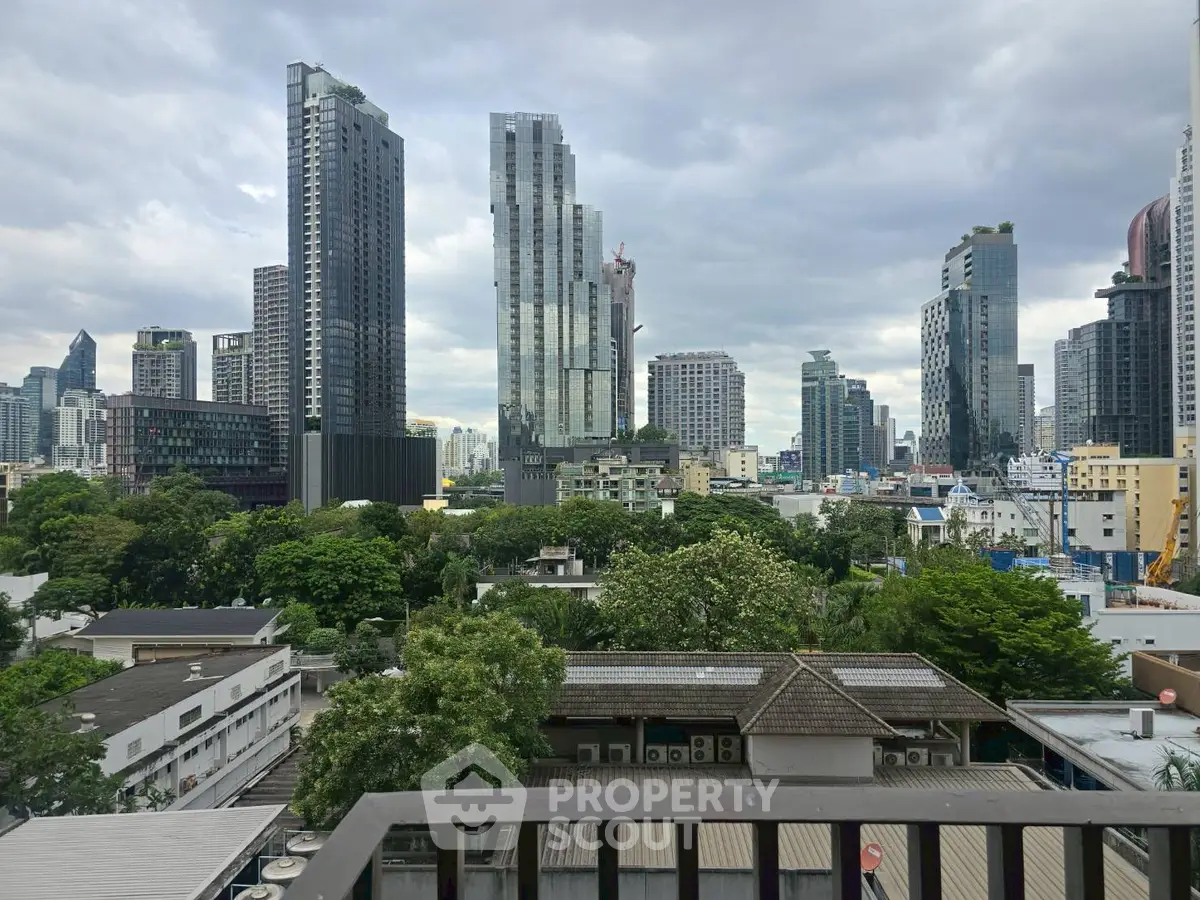 Stunning cityscape view from a balcony overlooking modern skyscrapers and lush greenery.