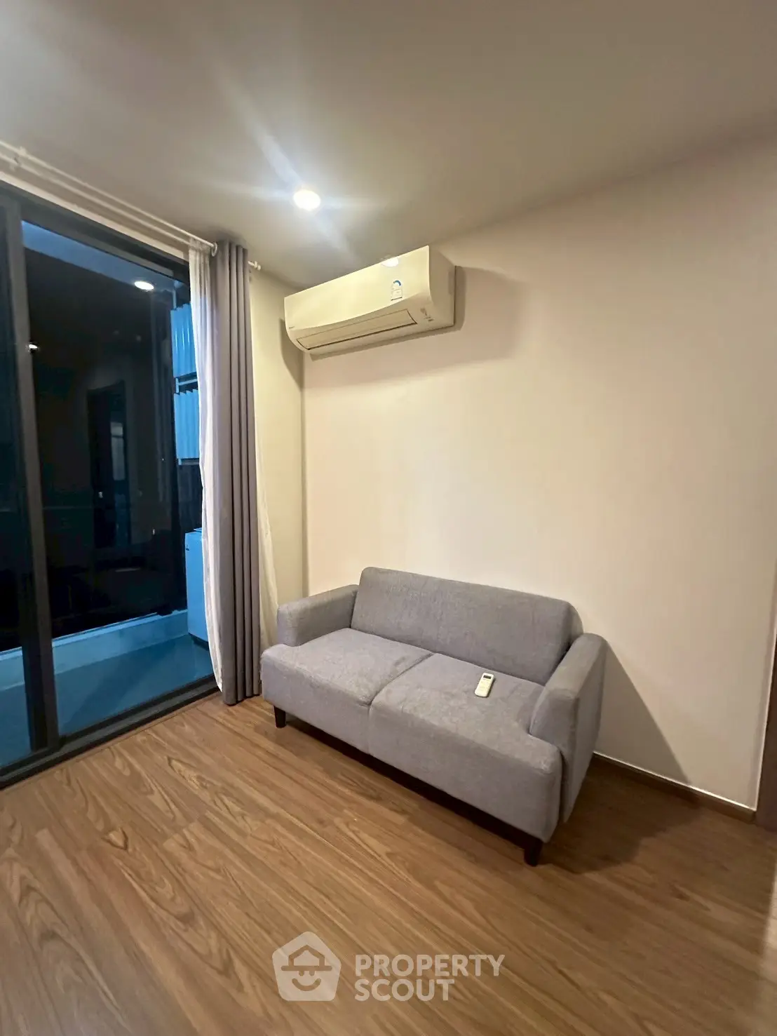Modern living room with sleek sofa and air conditioning, featuring a balcony view.