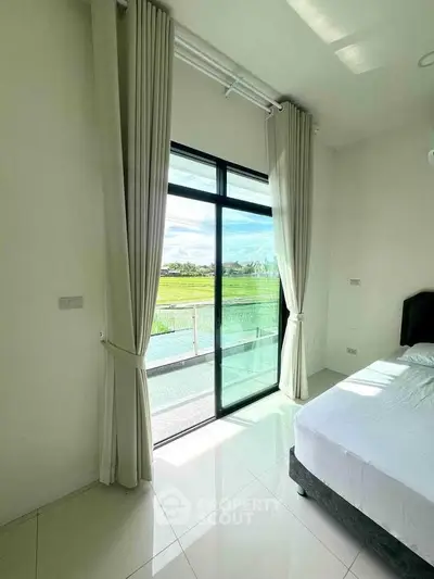 Bright bedroom with large window and scenic view of greenery.