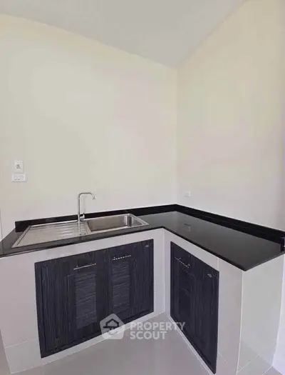 Modern kitchen with sleek black countertops and built-in sink, perfect for contemporary living.