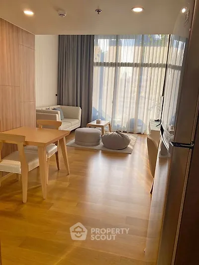Modern living room with wooden flooring, stylish furniture, and large windows for natural light.