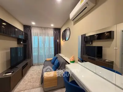 Modern living room with sleek furniture and large TV, featuring a stylish mirror and air conditioning.