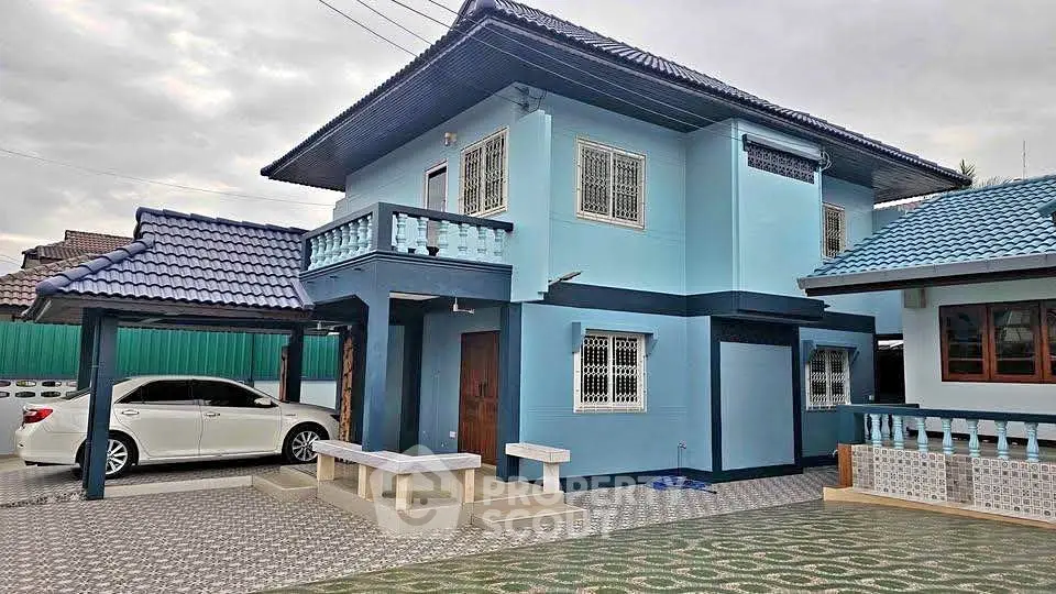 Charming two-story blue house with carport and tiled patio in a serene neighborhood.