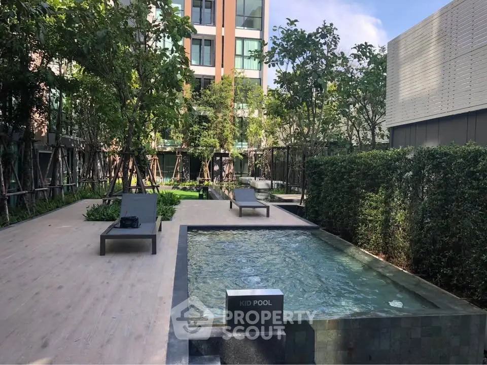 Modern condo pool area with lush greenery and sun loungers