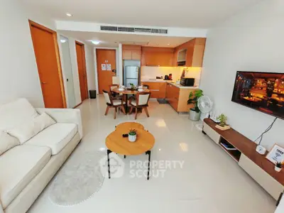 Modern open-plan living room with kitchen, featuring sleek furniture and bright lighting.