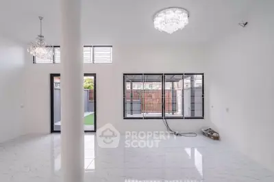 Spacious modern living room with elegant chandeliers and large windows for natural light.