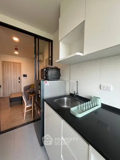 Modern compact kitchen with sleek black countertop and integrated appliances in a stylish apartment.