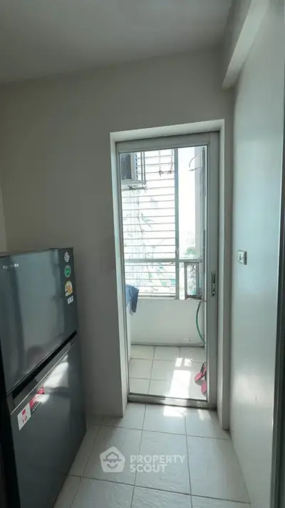 Modern kitchen with sleek fridge and balcony access, offering natural light and ventilation.