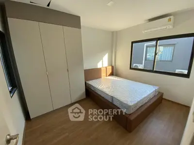 Modern bedroom with large window and built-in wardrobe, featuring sleek design and natural light.