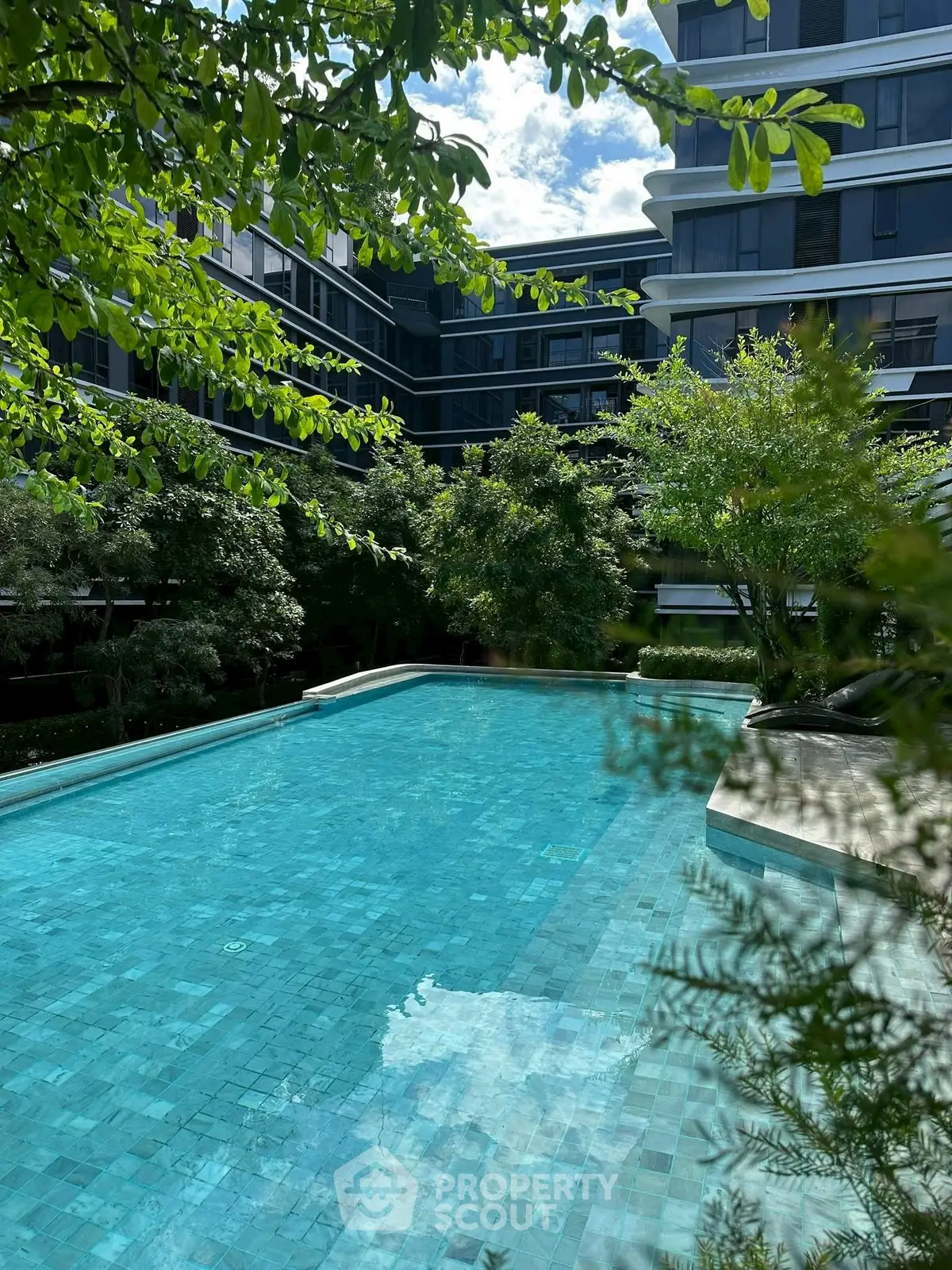 Luxurious residential pool surrounded by lush greenery and modern architecture.