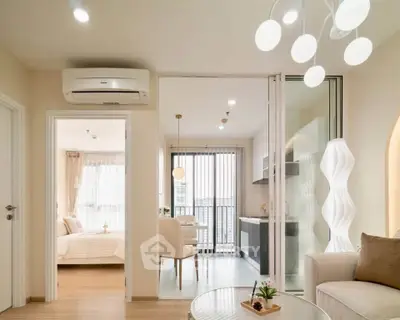 Modern open-plan living room with stylish lighting and cozy bedroom view.