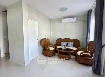 Charming living room with wicker furniture and modern air conditioning unit.