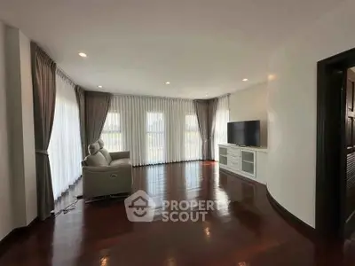 Spacious living room with elegant curtains and hardwood flooring, featuring a modern TV setup.