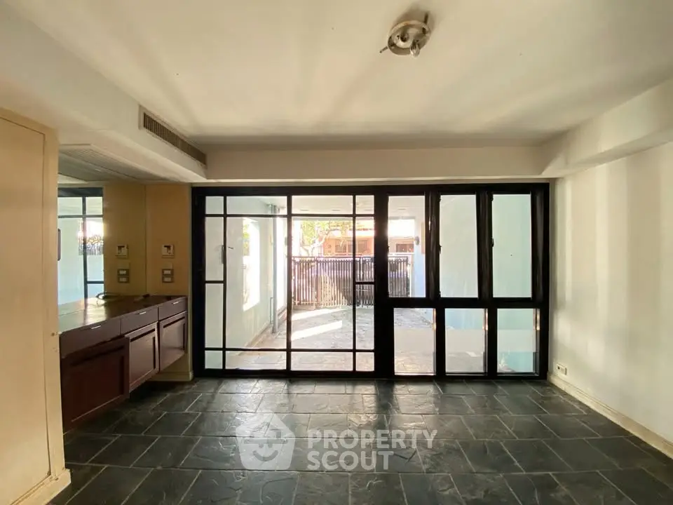 Spacious living room with large windows and stone tile flooring