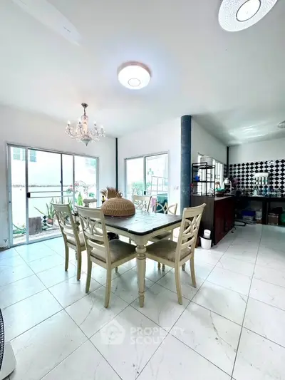 Spacious dining area with elegant chandelier and modern kitchen in open layout design.