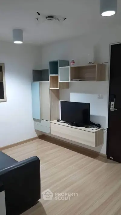 Modern living room with sleek TV unit and stylish shelving in a cozy apartment.