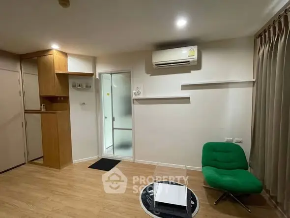 Modern living room with wooden flooring, green chair, and air conditioning unit.