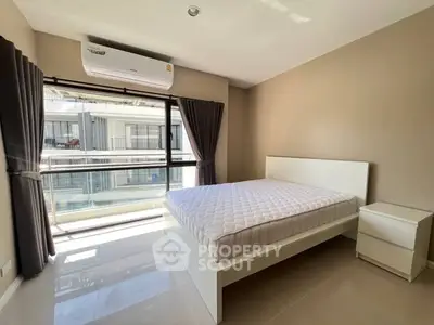 Bright bedroom with large window and modern furnishings in a stylish apartment.