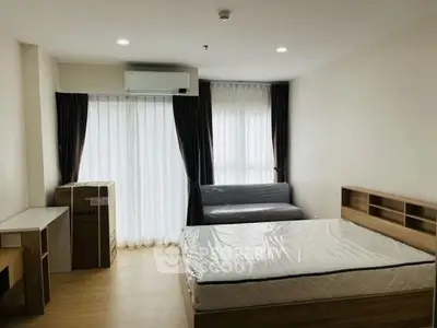 Modern bedroom with large windows and natural light, featuring a bed, sofa, and air conditioning.