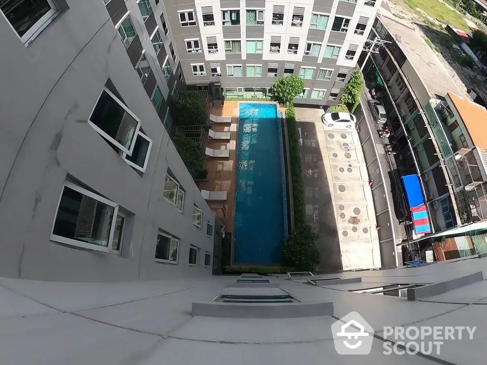 Modern apartment building with pool view from above, showcasing urban living amenities.