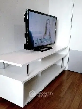 Modern living room with sleek white TV stand and flat-screen television.