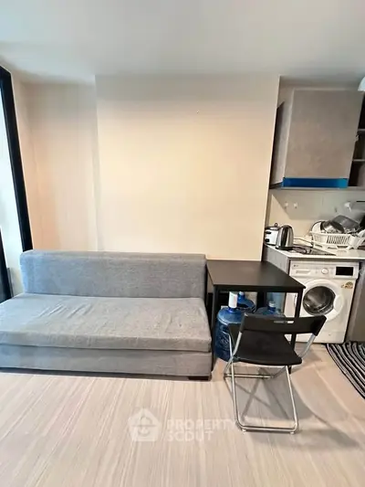 Modern compact living room with sofa, table, and washing machine in a cozy apartment.