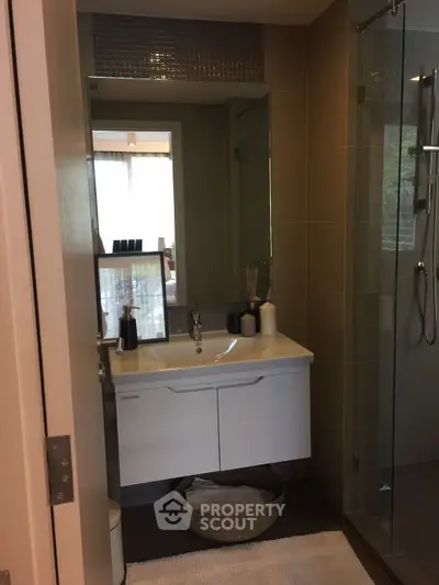 Modern bathroom with sleek vanity and glass shower in contemporary apartment.