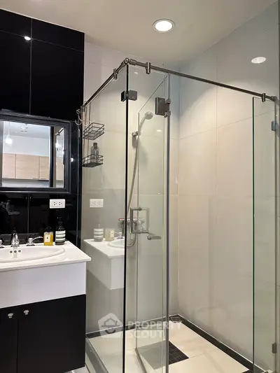 Modern bathroom with glass shower enclosure and sleek black and white design.