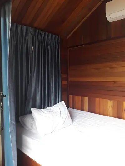 Cozy wooden bedroom with air conditioning and curtains for privacy.