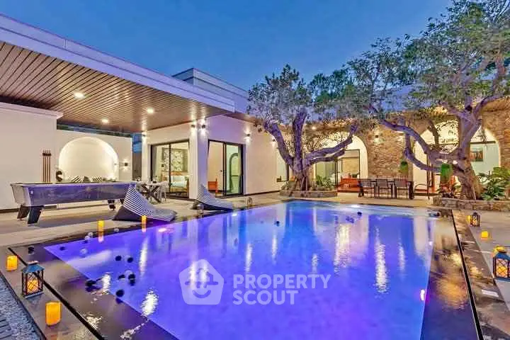 Luxurious modern villa with illuminated pool and stylish outdoor seating area.