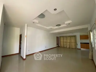 Spacious unfurnished living room with modern ceiling design and large windows.