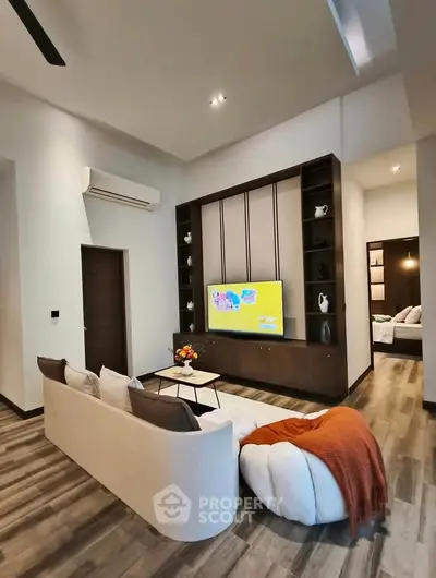 Modern living room with stylish decor and wall-mounted TV, featuring cozy seating and elegant shelving.