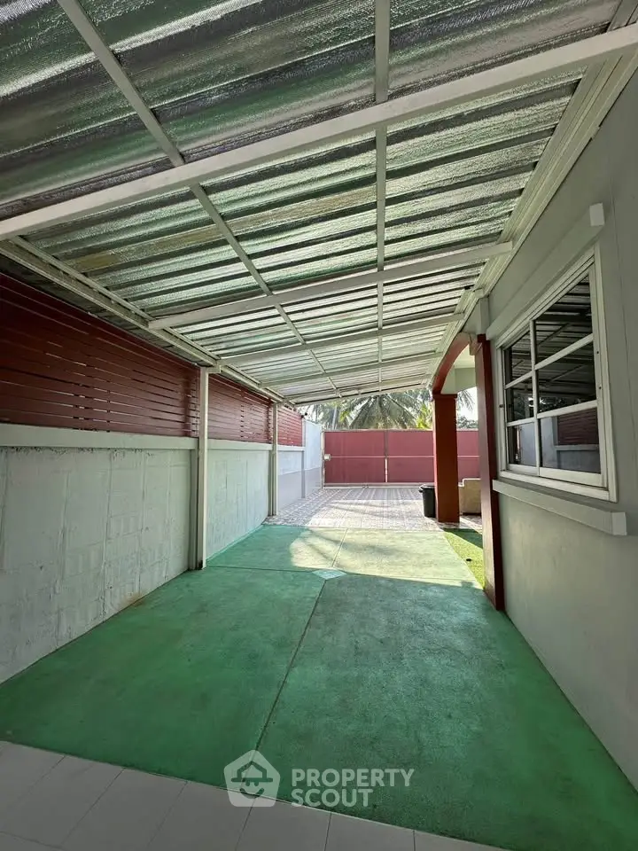 Spacious covered outdoor area with green flooring and ample natural light, perfect for relaxation or storage.