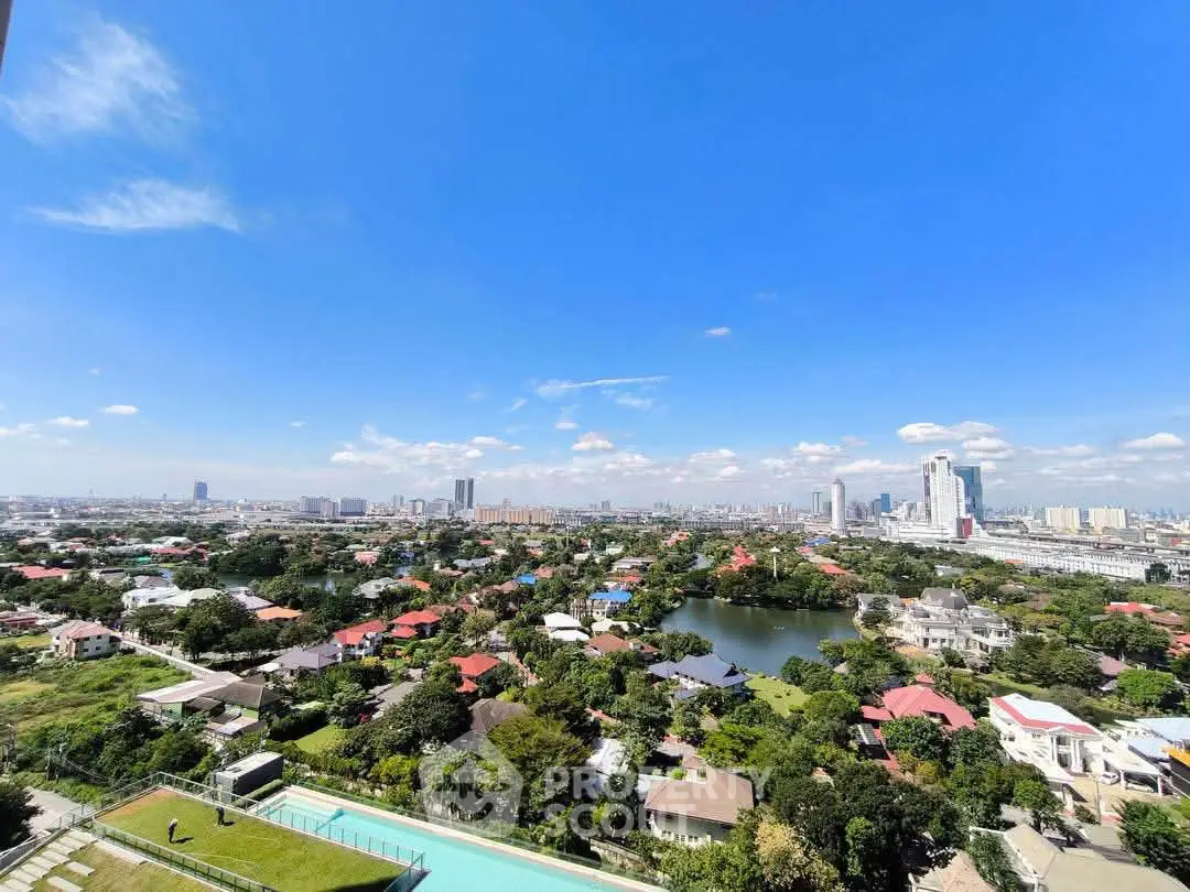 Stunning cityscape view from high-rise building with clear blue sky and lush greenery.