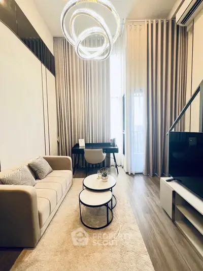 Modern living room with elegant chandelier and cozy seating area, featuring floor-to-ceiling curtains and stylish decor.