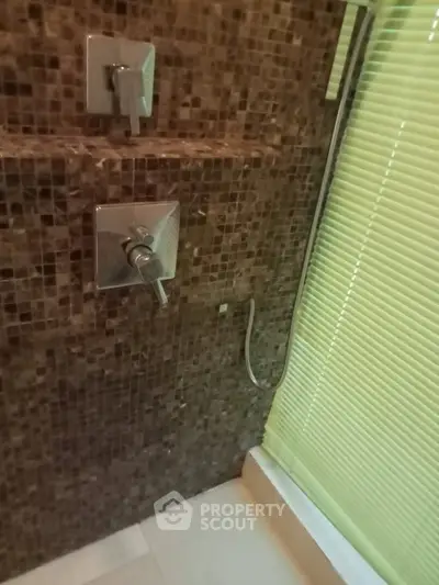 Modern bathroom with stylish mosaic tiles and sleek shower fixtures.