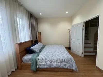 Spacious bedroom with modern decor and wooden flooring, featuring a cozy bed and ample natural light.