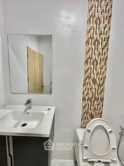Modern bathroom with stylish mosaic tile accent and sleek fixtures.