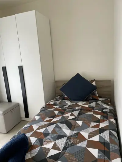 Cozy bedroom with modern geometric bedding and sleek wardrobe design.