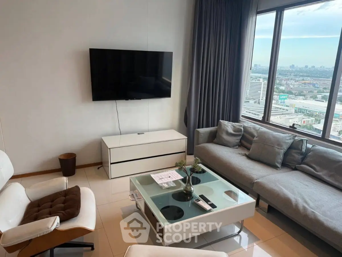 Modern living room with large windows offering stunning city views, sleek furniture, and a wall-mounted TV.