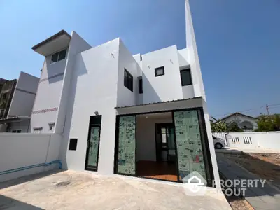 Modern white two-story house with large windows and spacious driveway