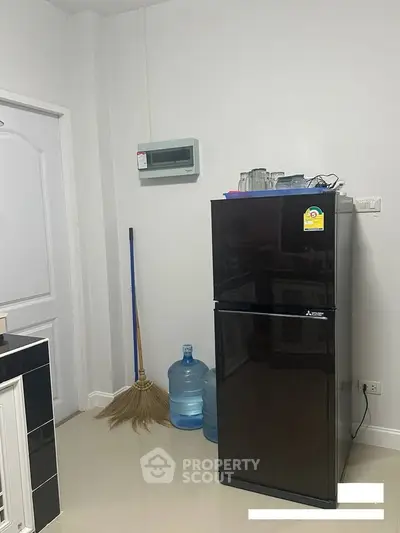 Modern kitchen corner with sleek black fridge and essential appliances.