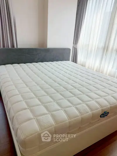 Spacious bedroom with large bed and natural light from floor-to-ceiling windows.