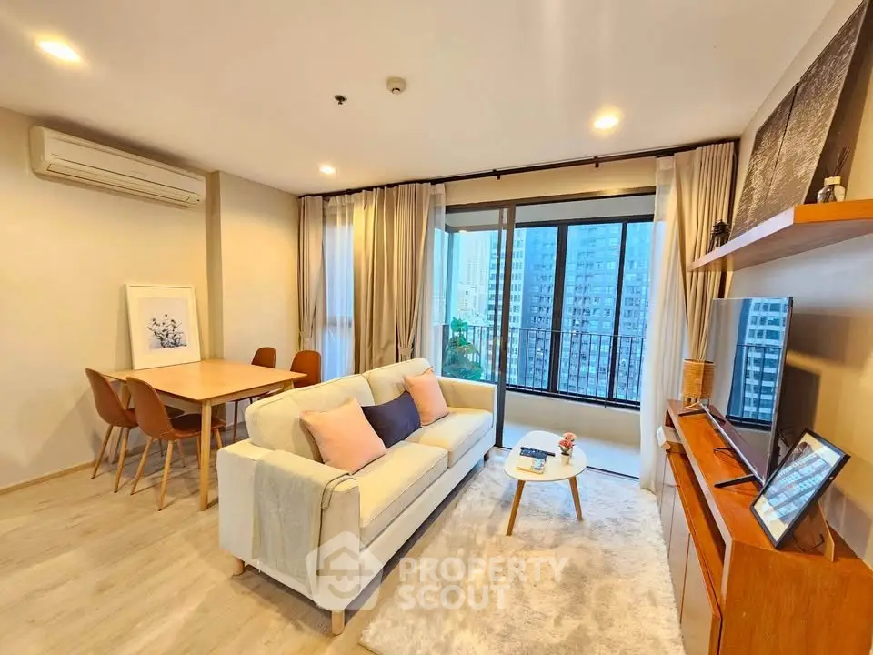 Modern living room with cozy decor and city view balcony in high-rise apartment.