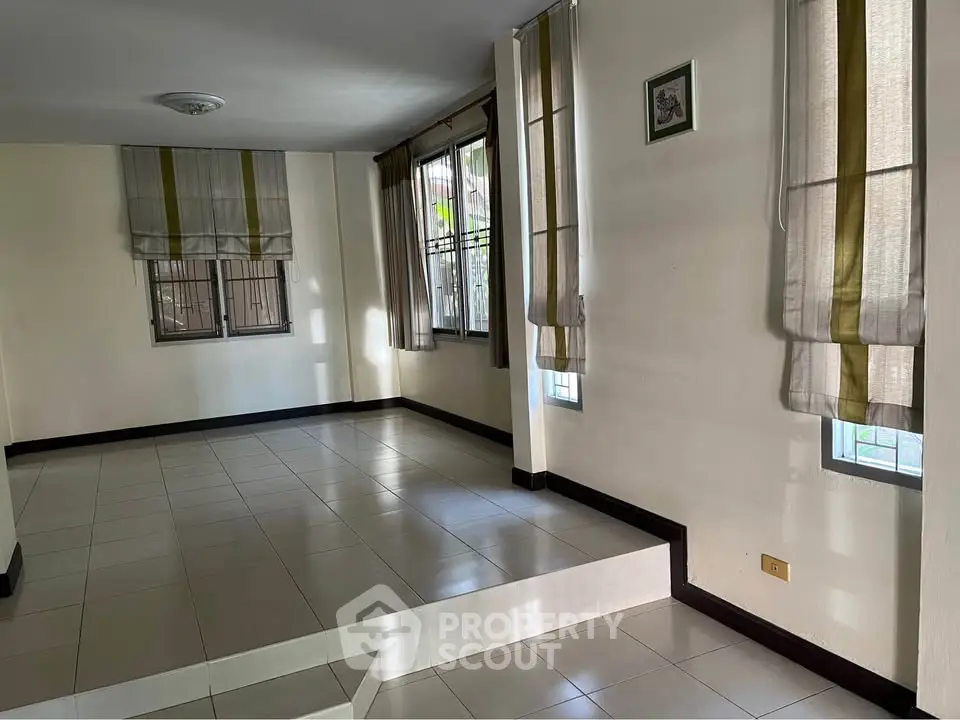 Spacious tiled room with large windows and elegant curtains, perfect for versatile living space.