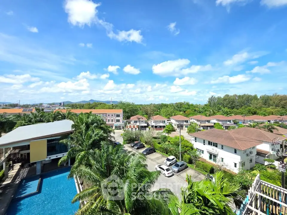 Stunning aerial view of residential area with pool and lush greenery under a bright blue sky.