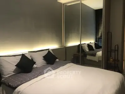 Modern bedroom with stylish lighting and mirrored wardrobe in a cozy apartment.