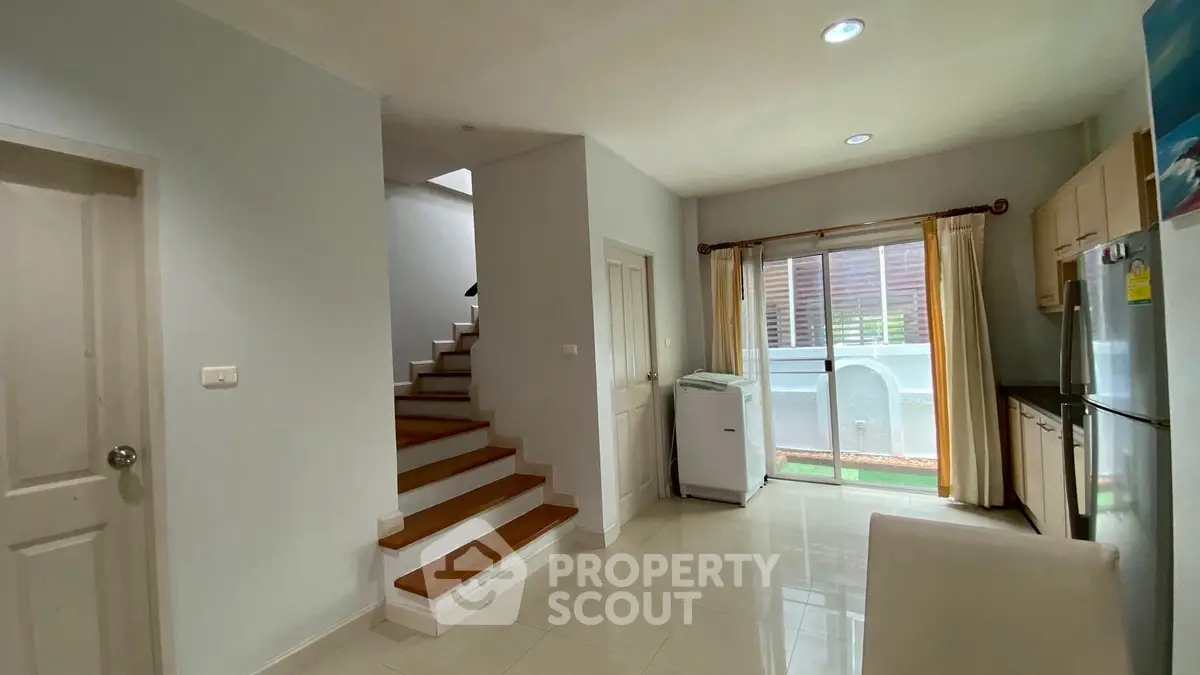 Modern interior with staircase and kitchen area, featuring sleek design and natural light.