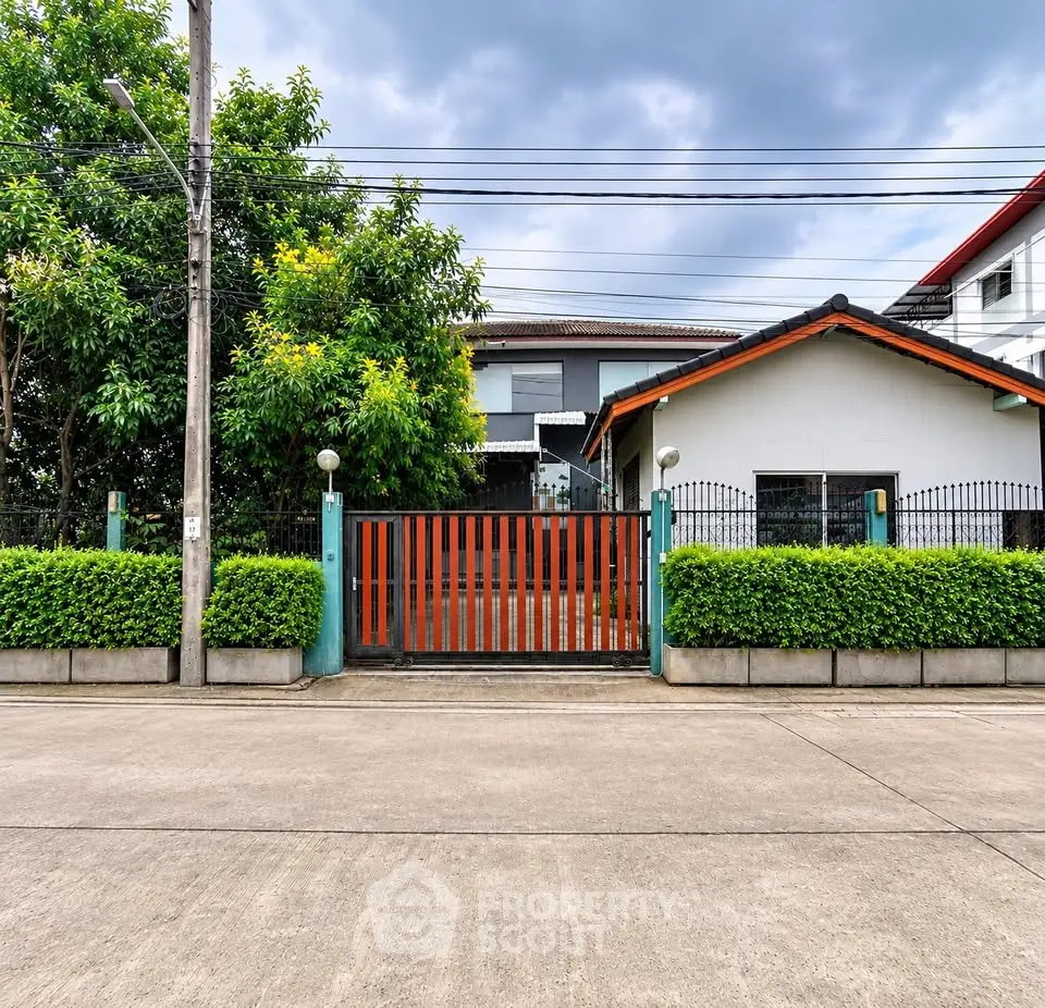 Charming suburban house with modern gate and lush greenery, perfect for family living.